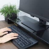 デスクトップパソコンとキーボードに乗っている女性の手